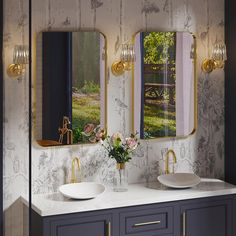 two sinks in a bathroom with wallpapered walls and mirrors above them are gold faucets