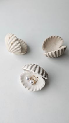 three seashells with pearls on them sitting on a white counter top next to each other