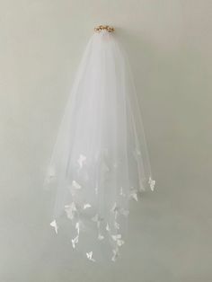 a white veil hanging on the wall with butterflies attached to it's back side