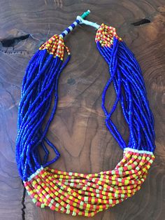 "Gorgeous vintage African glass trade bead statement necklace. It has 20 strands of glass trade beads with stunning cobalt blue, red, and yellow colors. Unique clasp featuring turquoise color beads. Necklace Measures 25\"." Traditional Multicolor Necklace With Faceted Beads, Artisan Multicolor Multi-strand Beaded Necklaces, Hand-strung Multicolor Jewelry For Festivals, Hand-strung Multicolor Festival Jewelry, Artisan Multicolor Multi-strand Beads, Artisan Blue Beaded Necklaces For Festivals, Multicolor Hand-strung Jewelry For Festivals, Festival Blue Beaded Necklaces With Colorful Beads, Vibrant Blue Round Bead Jewelry