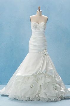 a white wedding dress on display in front of a blue wall and floor length mannequin