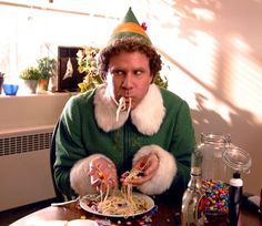 the man is eating noodles with his mouth wide open while sitting at a table in front of him