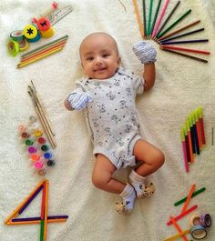 a baby laying on top of a blanket surrounded by crayons and pencils