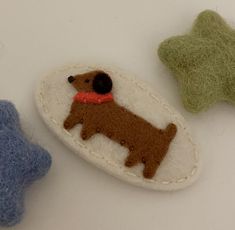 three felt animals sitting next to each other on a white counter top, one brown dog and one green star