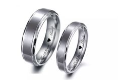 two wedding rings with hearts engraved on the side and one has a black diamond in it