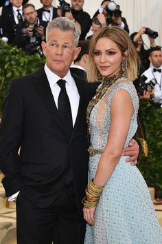 a man and woman standing next to each other in front of photographers on the red carpet