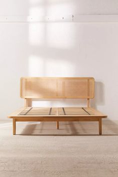 a wooden bench sitting in the middle of a room next to a window with sunlight streaming through it