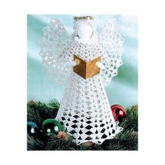 a crocheted angel with a book in its hands on top of pine needles