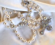 "This new addition to my Catholic rosary collection is created using gorgeous 8mm Swarovski Pearls PLUS imported 10 mm Pearls with rhinestone trim!  Each pearl is separated by 5mm AB Swarovski crystals.  The extra glistening, shimmering, pops of every color of the rainbow on the rhinestone crystal-studded cross is over-the-top sparkly!   This Rosary will soon become a cherished heirloom for you or someone you love.   This crystal Rosary is simply stunning and really makes a statement. It would make a beautiful bride's Rosary to carry or drape from her floral bouquet.   This beautiful Rosary is created using only the finest, authentic Swarovski pearls and crystals, famous for their color, sparkle, and quality!  The shimmering, glittering, light that reflects from the AB finish on the Swarov Elegant White Rosary For Wedding, Elegant White Wedding Rosary, Elegant Pearl White Rosary For Wedding, Elegant Silver Wedding Rosary, Elegant Beaded Wedding Rosary, Luxury Brides, Rhinestone Trim, Rhinestone Studs, Swarovski Pearls