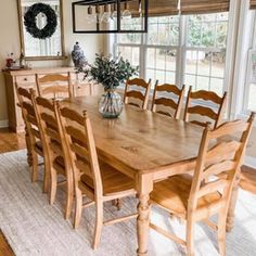 a dining room table and chairs in front of a large window with wreaths on it