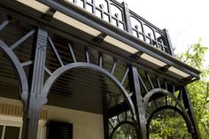 an ornate ironwork design on the side of a building with trees in the background