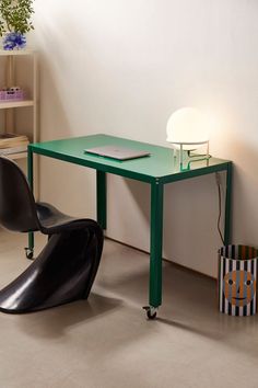 a green table and chair in a room with a lamp on the wall next to it