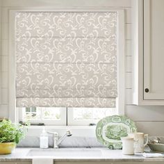 a kitchen window covered in roman shades