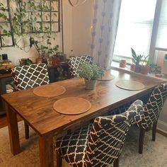 a dining room table with blue and white patterned chairs next to a potted plant