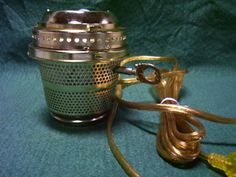 an old fashioned tea kettle is sitting on a green surface with a cord attached to it