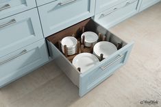 an open drawer in the middle of a kitchen with plates and cups on it's sides