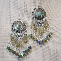 "Ornate beaded boho styling in these silver chandelier earrings. Beads are wire wrapped AB glass cube beads, green crystal beads and aqua glass beads that have an AB quality for extra shine and color. The beaded segments are linked on ornate silver metal filigree. The length of these earrings is 2 3/8\" from silver plate ear wire link. The width is 1 1/2\" at widest point on the base. Silver segment measures 1\" across. All of my jewelry items come boxed and lace ribbon tied and tagged for easy Bohemian Beaded Chain Earrings, Bohemian Beaded Chain Dangle Chandelier Earrings, Bohemian Beaded Chandelier Dangle Earrings, Bohemian Style Chandelier Earrings With Faceted Beads, Bohemian Chandelier Earrings With Beaded Chain, Bohemian Chandelier Earrings With Faceted Beads, Bohemian Chandelier Earrings With Colorful Beads For Festivals, Bohemian Chandelier Dangle Earrings With Faceted Beads, Bohemian Dangle Earrings With Faceted Beads