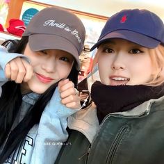 two young women wearing hats and jackets posing for a photo in front of the camera