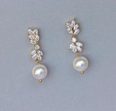 two pairs of pearl and crystal earrings on a gray surface with white background, closeup