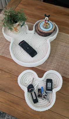 two mickey mouse shaped trays with keys and remote controls on them sitting on top of a wooden table