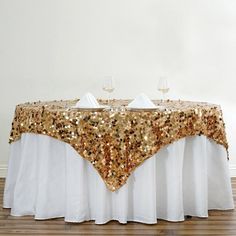 a table with gold sequins on it and two wine glasses at the top