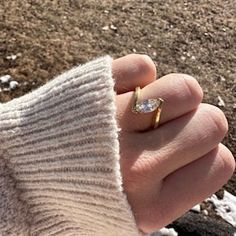 a person's hand wearing a gold ring with a small diamond on the middle