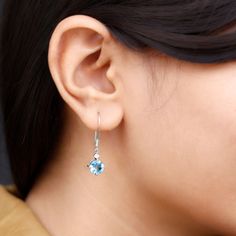 Product Details These elegant drop earrings feature stunning round shape swiss blue topaz stone, and shimmering Moissanite set in prong setting. The earrings are crafted in luxurious gold and hang from delicate fish hook backs, adding a touch of sophistication to any outfit. The beautiful blue topaz stone are offset by the glittering Moissanite, creating a mesmerizing and eye-catching look. These classic earrings are the perfect accessory for adding a pop of color and sparkle to any outfit, maki Fine Jewelry Topaz Earrings With Prong Setting, Blue Topaz Round Earrings For Anniversary, Elegant Blue Topaz Earrings With Prong Setting, White Gold Drop Earrings With Blue Topaz, White Gold Blue Topaz Drop Earrings, Blue Topaz Teardrop Birthstone Earrings, Teardrop Blue Topaz Birthstone Earrings, Blue Topaz Birthstone Drop Earrings, Elegant Blue Topaz Earrings With Ear Wire