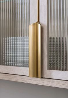 a gold door handle on the side of a wooden door with blinds in the background