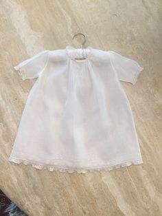 "A lovely vintage batiste baby dress with matching slip.  The neckline and sleeves are edged in lace. The neckline features three dainty embroidered flowers with multiple lines of small tucks on both sides. The same embroidered design and multiple lines of stitching appears at the hemline which ends in lace. The back has a two button closure. The matching slip has a lace edged neckline and the same hemline detail as the dress. The dress and slip are in excellent condition.    18.5\" length shoulder to hem    15\" from side to side under the arms" Classic Broderie Anglaise Dresses For Daywear, Classic Broderie Anglaise Dresses For Daytime, Classic Dresses With Broderie Anglaise For Daywear, Classic Short Sleeve Dress For Baptism, Classic Fitted Baptism Dress With Broderie Anglaise, White Short Sleeve Baptism Dress For Daywear, White Baptism Dress With Short Sleeves For Daywear, Classic Lace Dress For First Communion, Classic Lace Trim Dress For Daywear