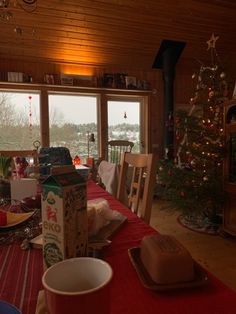 a dining room table set for christmas with presents on the table and a large window in the background