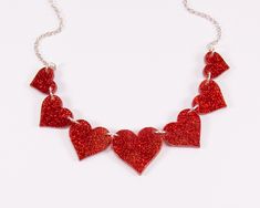 "A red glitter heart necklace. Made from laser-cut acrylic. Perfect for adding a bit of sparkle to your outfit. The necklace is made from multiple pieces of glitter acrylic linked together with jumpings and chain, which means it moves and flexes with your body so is comfortable and lightweight to wear. It comes on an 18\" silver plated (Nickle free) chain with a 6cm chain extender, so you can wear it at your prefered height. It comes in one of our Ey Up Chuck branded gift boxes, making it gift-r