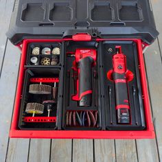 a red tool box filled with tools on top of a wooden floor next to a black case