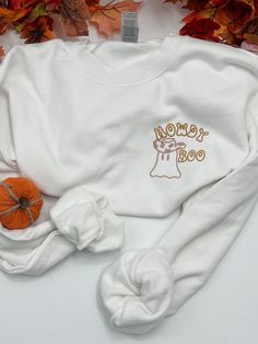 "Get ready to say \"Howdy Boo\" with our Embroidered Halloween Sweatshirt! This playful and adorable sweatshirt features a charming Halloween Cowboy Ghost that's sure to put a smile on your face. Whether you're looking for a cute and cozy outfit for the spooky season or you want to add a touch of whimsy to your wardrobe, this sweatshirt is the perfect choice. Embrace the Halloween spirit and spread some \"Howdy Boo\" vibes wherever you go with this delightful embroidered sweatshirt!  Our Gildan sweatshirt is made from a blend of 50% cotton and 50% polyester, ensuring comfort and durability. It features a classic fit with no center crease and a 1x1 athletic rib knit collar with spandex for added flexibility.  Experience ultimate comfort with our Comfort Colors shirt. Made from 9.5 oz. 80/20 Halloween White Sweatshirt With Embroidered Graphics, White Halloween Sweatshirt With Embroidered Graphics, Halloween White Embroidered Sweatshirt, Halloween Embroidered Long Sleeve Tops, Cow Ghost, Ghost Cow, Halloween Cowboy, Halloween Cow, Embroidered Halloween