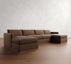 a brown sectional couch sitting on top of a wooden floor next to a white wall