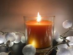 a lit candle sitting on top of a table next to some white pom - poms