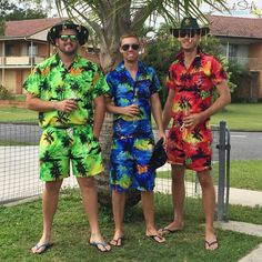 three men standing next to each other in front of a palm tree wearing colorful clothing