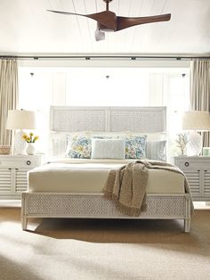 a bedroom with a bed, nightstands and ceiling fan in the middle of it