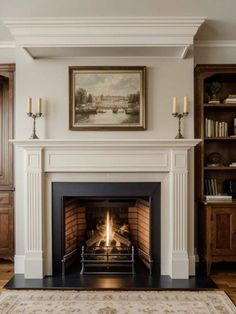 a fire place in a living room with a painting on the wall and bookshelves