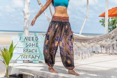 a woman standing on the beach in front of a hammock