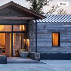 a house with wooden sidings and glass windows on the front door is lit up at night