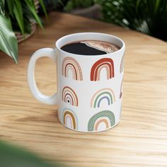 there is a coffee cup with a rainbow pattern on it and a plant in the background