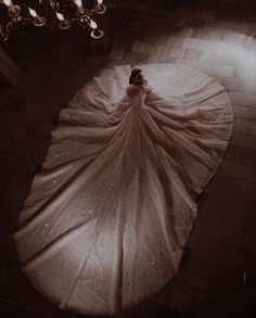 a woman in a wedding dress laying on the floor with a chandelier above her