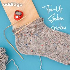 a pair of socks with knitting needles next to it and yarn on a blue background