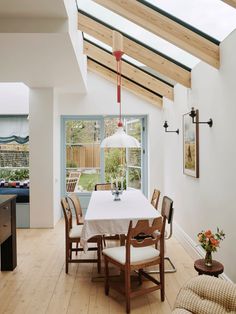 a dining room table with chairs and a white table cloth on it in front of a window