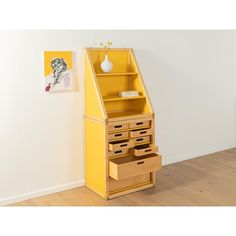 a yellow cabinet with drawers in the corner next to a white wall and wooden floor