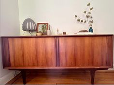 a wooden sideboard sitting on top of a hard wood floor next to a plant