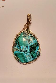 Bold Slide pendant featuring a beautiful 40x50mm gemstones with vibrant green Malachite and Caribbean blue Chrysocolla. It is hand crafted in 14K Yellow gold filled wire.  It has a 9x10mm bail opening to fit nearly any thickness of chain or up to a 10mm omega.  It measures approximately 2 3/4 inches long.  Looking for a certain color? Just ask!!  Matching earring charms are sold separately in my store.  All measurements are as close as possible within the limitations and restrictions imposed by Artisan Gold Chrysocolla Jewelry, Elegant Green Chrysocolla Jewelry, Chrysocolla Gemstone Oval Pendant Jewelry, Green Chrysocolla Pendant Jewelry, Green Malachite Cabochon Jewelry, Artisan Malachite Gemstone Jewelry, Gold Bohemian Jewelry With Malachite, Green Chrysocolla Gemstone Jewelry, Gold Bohemian Malachite Jewelry