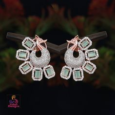 Emerald cut American diamond stone, peacock earrings in silver or rose gold background. Embellished with clear rhinestone crystals, the statement earrings is designed in a dancing peacock motif. Elegant Hand Set Rose Gold Earrings, Elegant Hand-set Rose Gold Earrings, Elegant Rose Gold Hand Set Earrings, Dazzling Rose Gold Cubic Zirconia Bridal Earrings, Diamond-plated Earrings For Party, Peacock Design Drop Earrings For Party, Rose Gold Diamond Earrings For Party, Rose Gold Pierced Jewelry With Cubic Zirconia, Pierced Rose Gold Jewelry With Cubic Zirconia