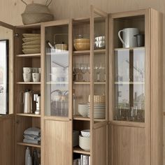 an open cabinet with dishes and cups on it in a room that has wood paneling