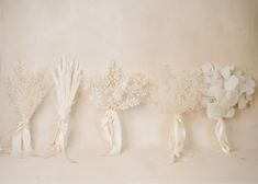 three bouquets of flowers are lined up against a wall with ribbons tied around them